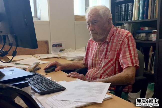 David Goodall sits at an office desk behind a computer.